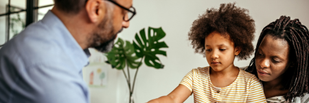 A mother and child sitting down with a practitioner. The mother and child are both facing the practitioner.