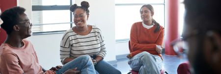 A group of people sit together in a circle, talking and laughing.