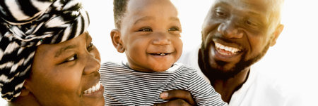 A baby being held up by two smiling parents.