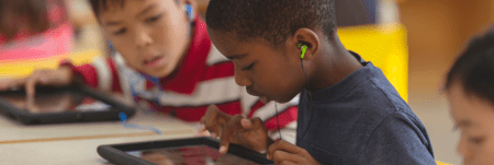 A child has earphones in and is using a tablet device.