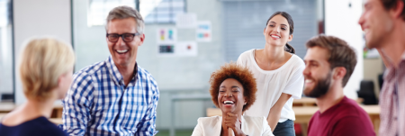 A group of colleagues laughing together in the office.