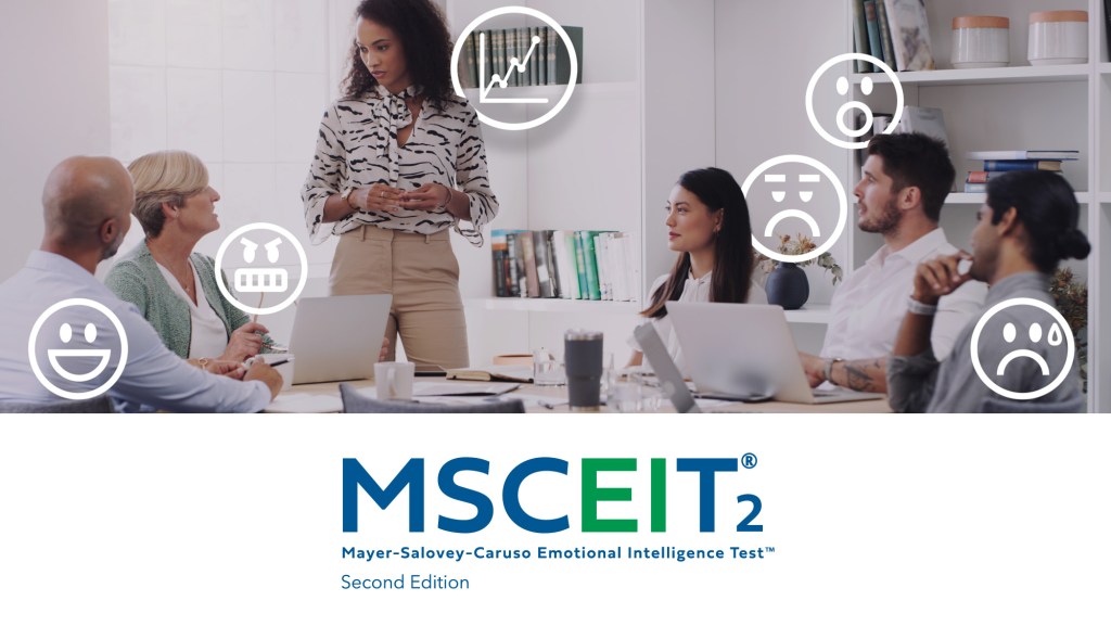 vaPeople sit around a conference table listening to a presenter at the front of the room. Emotion‑themed icons—such as happy, sad, surprised, and confused faces—are overlaid around the group. The MSCEIT² Mayer‑Salovey‑Caruso Emotional Intelligence Test logo appears below the scene.