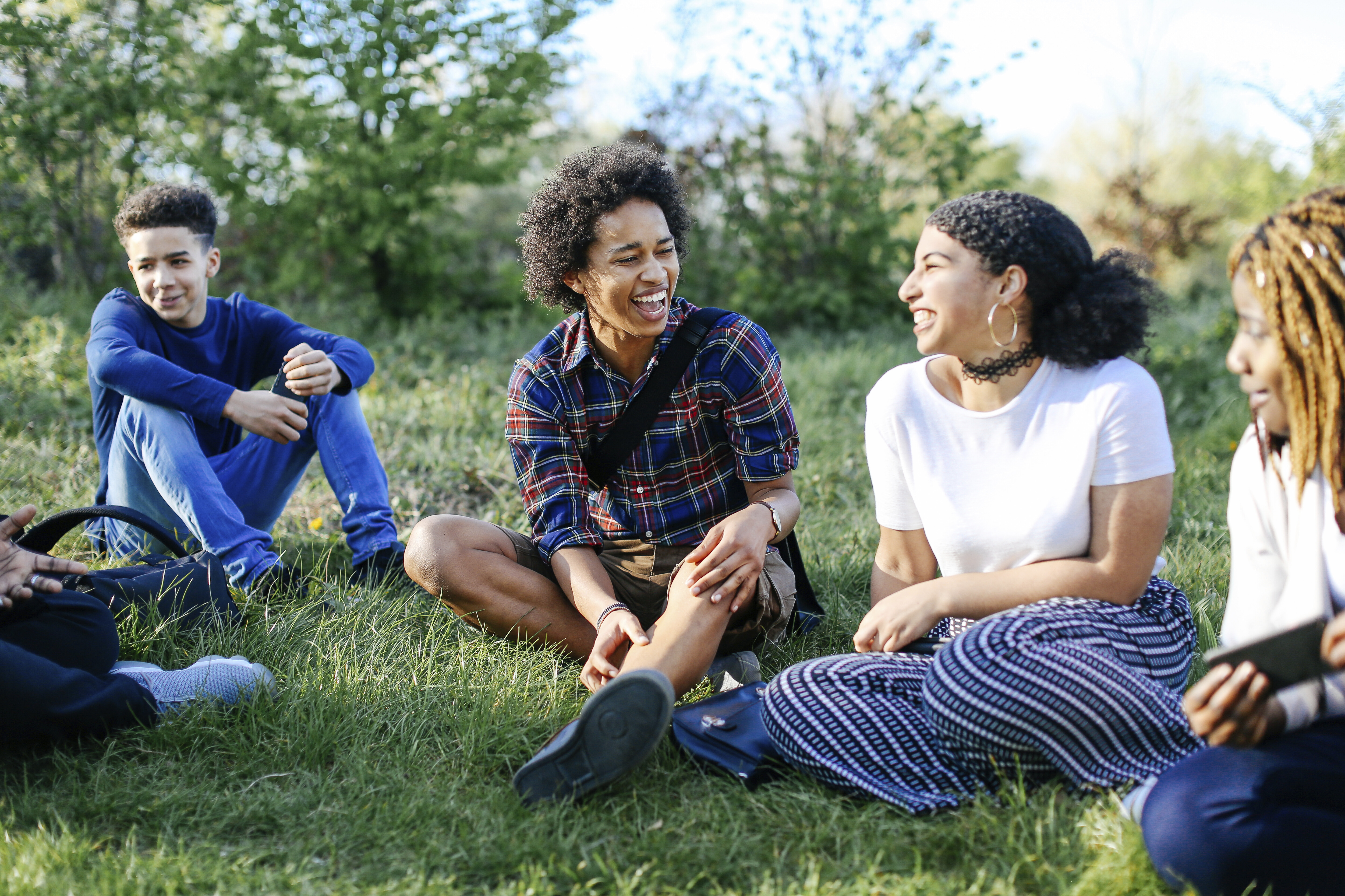 Group of friends sitting on grass, laughing